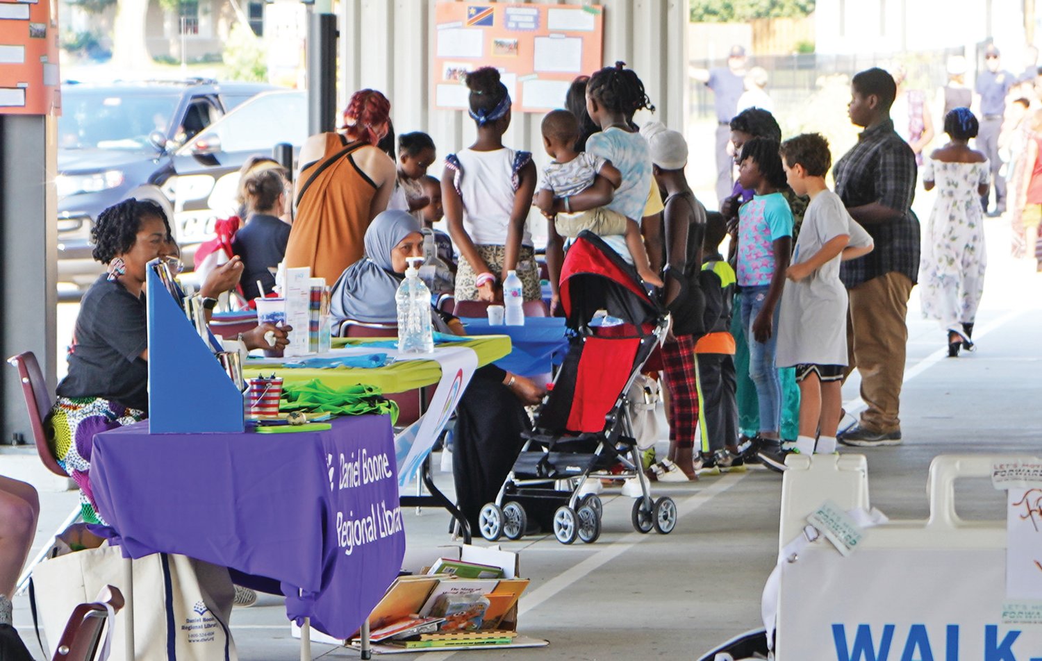 Participants in the 2021 World Refugee Day celebration gather around tables and booths under the MU Healthcare Pavilion in Clary-Shy Park in Columbia. The theme for the event was “Together, we heal, learn and shine.”